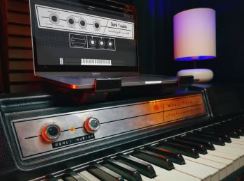 A Wurlitzer 200A electric piano with a laptop computer on top. A user interface for the Midnight Wurli library is displaying on the computer screen.
