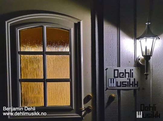 Sign with Dehli Musikk logo on house wall